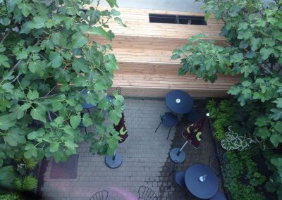 Stadstuin bij een eetterras in Gent: vijgenbomen zetten de toon, ondersteund door een weelderige schaduwbeplanting. Een gezellige groene plek voor een lunch of koffie (Folie à Deux, Gent)